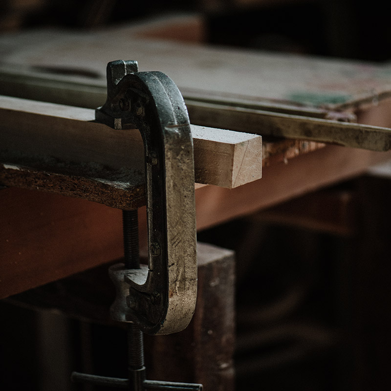 Woodworking vise clamps a wooden plank to a workbench in a dim workshop   Nerds On Site